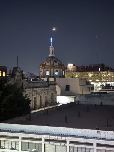 cityscape with a dome/temple in the background and the moon above it