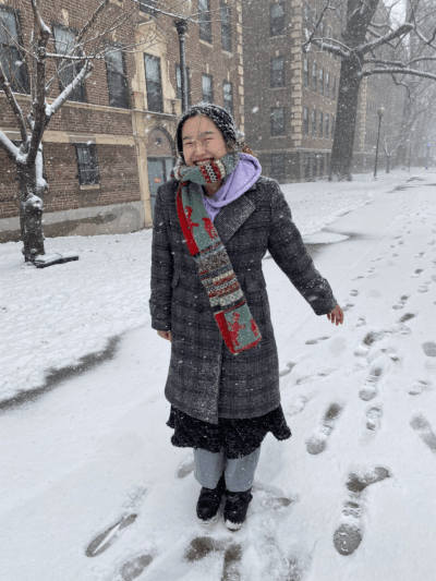 girl standing in snow, smiling, 2023 colourised