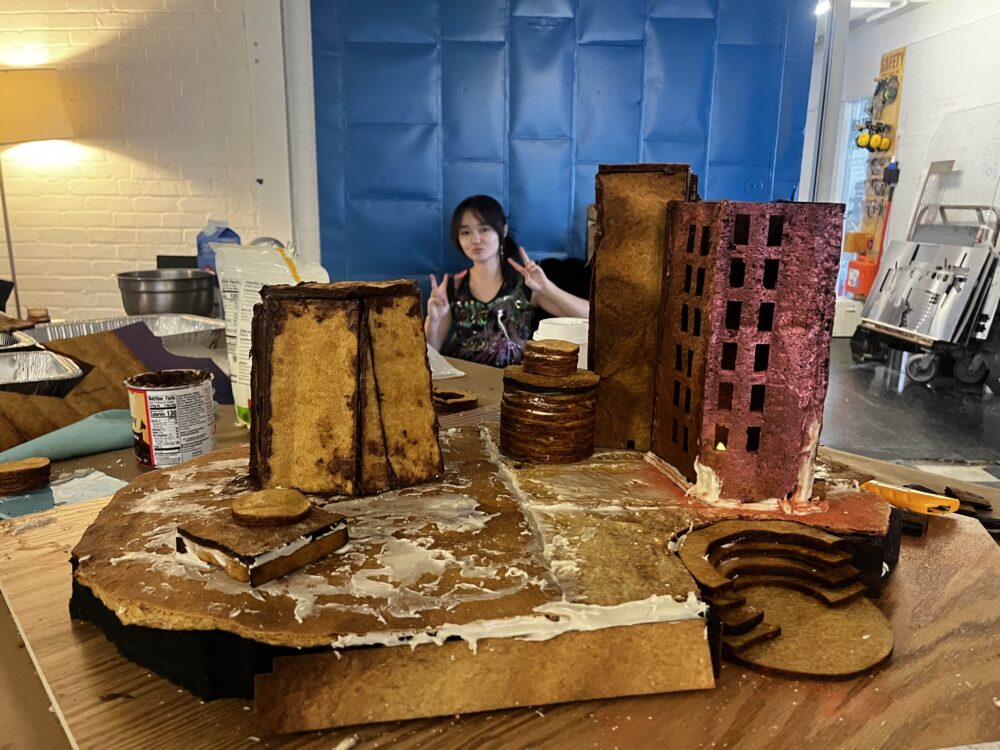 a girl posing behind a gingerbread structure