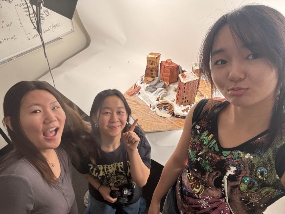 another selfie of people next to a gingerbread structure