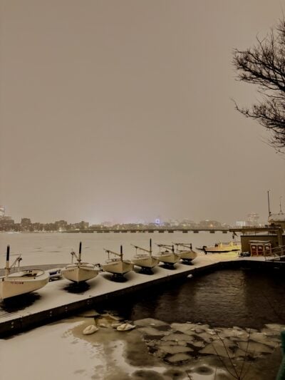 frozen charles river covered in a thick layer of snow, with docks and boats in foreground