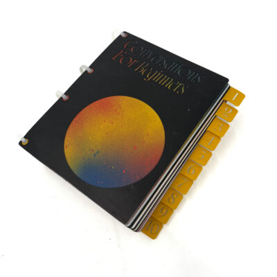 a picture of a black book bound with zipties with spray painted yellow tabs on the side