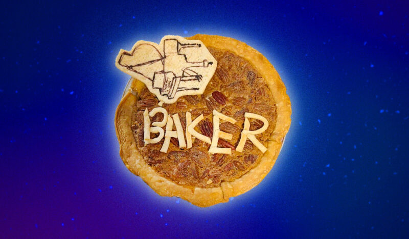 A pecan pie with crust on top spelling out BAKER and a drawing of a piano in edible marker.