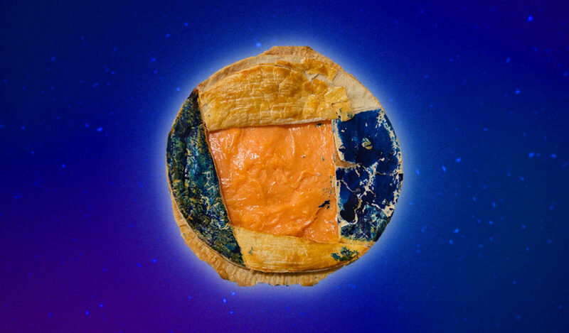 A pie with orange filling and blue dyed crust.