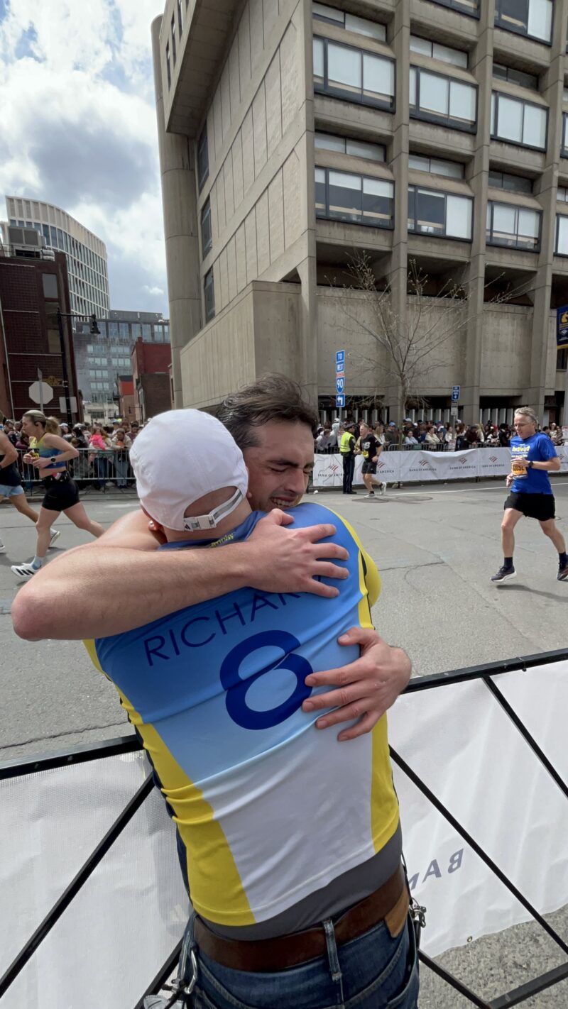 a photo of two people hugging near the boston marathon finish line 