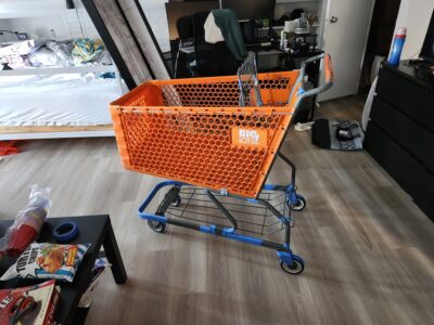 orange shopping cart with base covered in blue tape sitting in an apartment