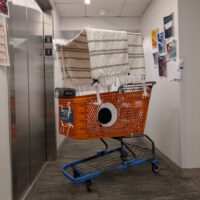 orange shopping cart in a hallway with large eyes on the side, a blanket canopy,&hellip;