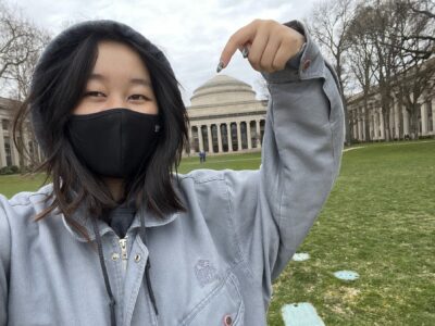 a girl takes a selfie in front of a dome, pointing her finger at the dome
