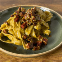 a plate of slightly greenish pasta with chorizo bits scattered on top