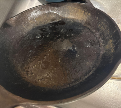 a sad, still wet cast iron pan with rust streaks sitting in the sink