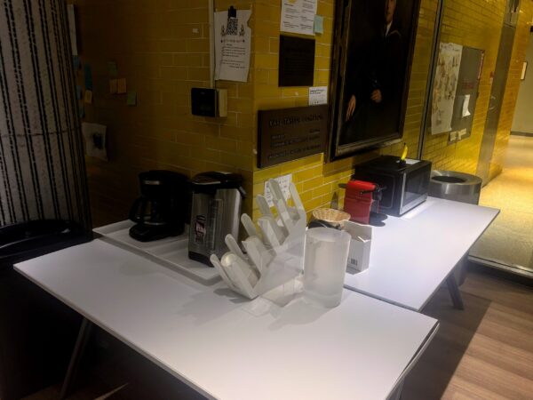 table besides a wall with coffee machines and plastic utensils
