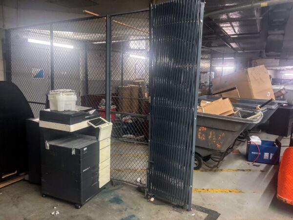 loading docks with printer and moving carts filled with wood scraps behind a fence 