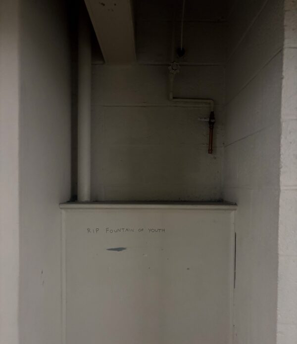 empty blank alcove in basement wall with "rip fountain of youth" written in sharpie