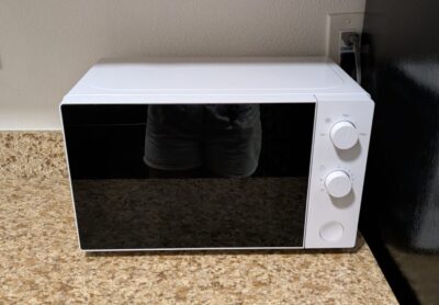 white microwave with a black door and two physical knobs as timers