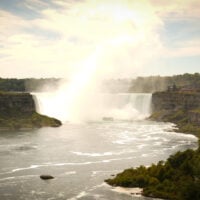 A wide waterfall and river gorge beneath a pale, hazy sky.