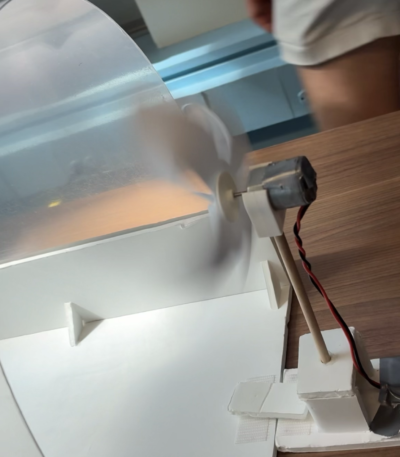 a small foam wind turbine spins under the influence of a fan