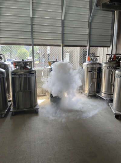 A big metal tank with nitrogen steam coming out of it.