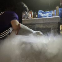 Person wearing safety goggles crouched overs steam.