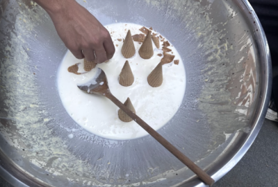 Ice cream cones in a puddle of whipped cream in a metal bowl