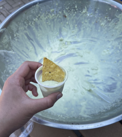 Tortilla chips in a cup with green ice cream and metal bowl in the background