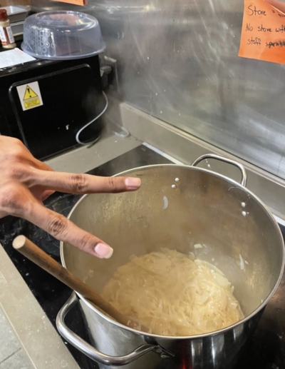 Hand in peace sign in front of a pot with sliced onions