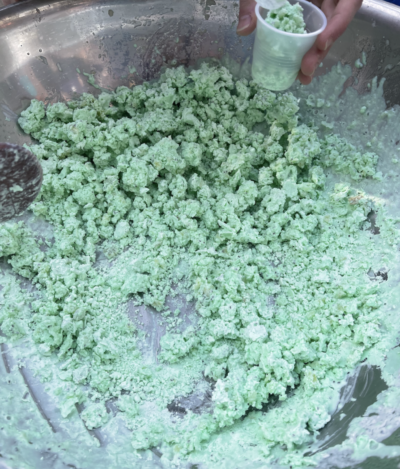 Lumps of green ice cream in a metal bowl