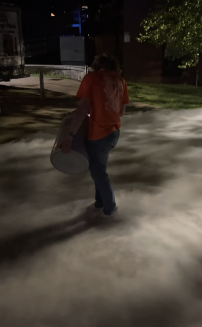 Person holding dewar with mist covering the ground at night