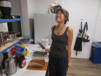 a happy girl holding a knife to cut into banana bread