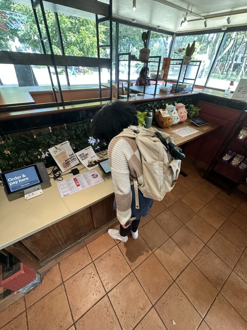 A picture taken from a high angle of Leya standing, hunched over a a tablet menu.
