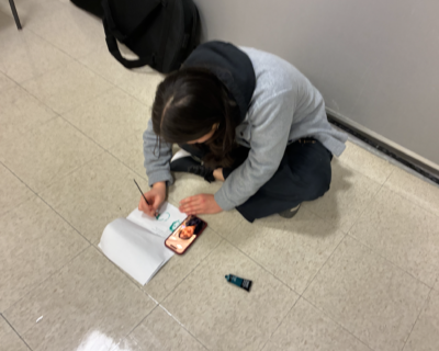elise is painting people's faces while sitting on the ground
