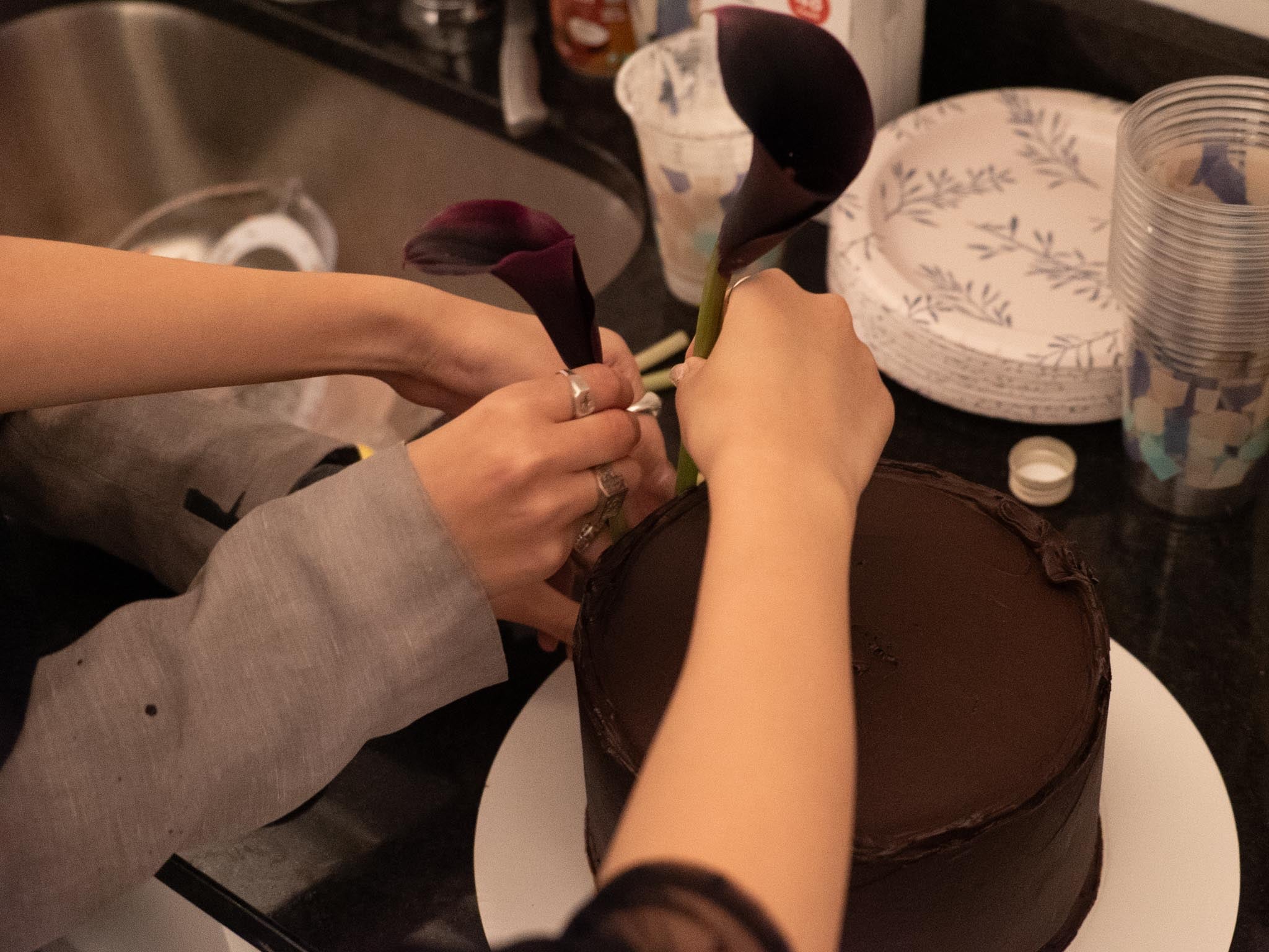 two people placing flower against chocolate cake