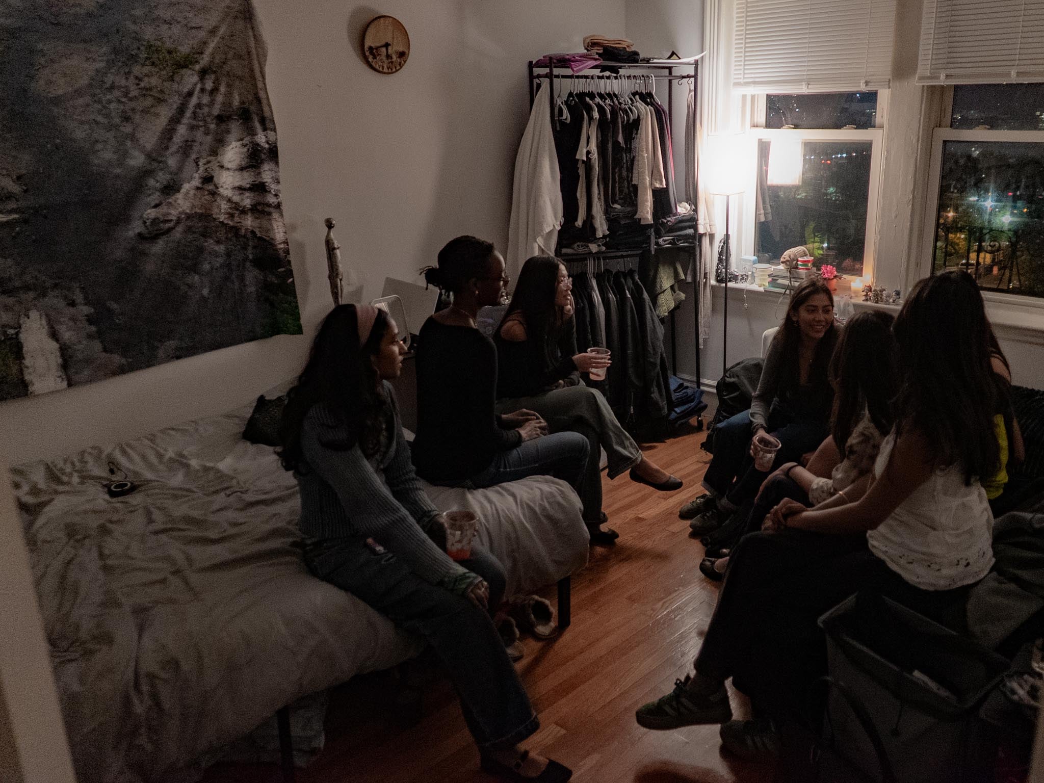 people sitting around dimly lit bedroom, chatting