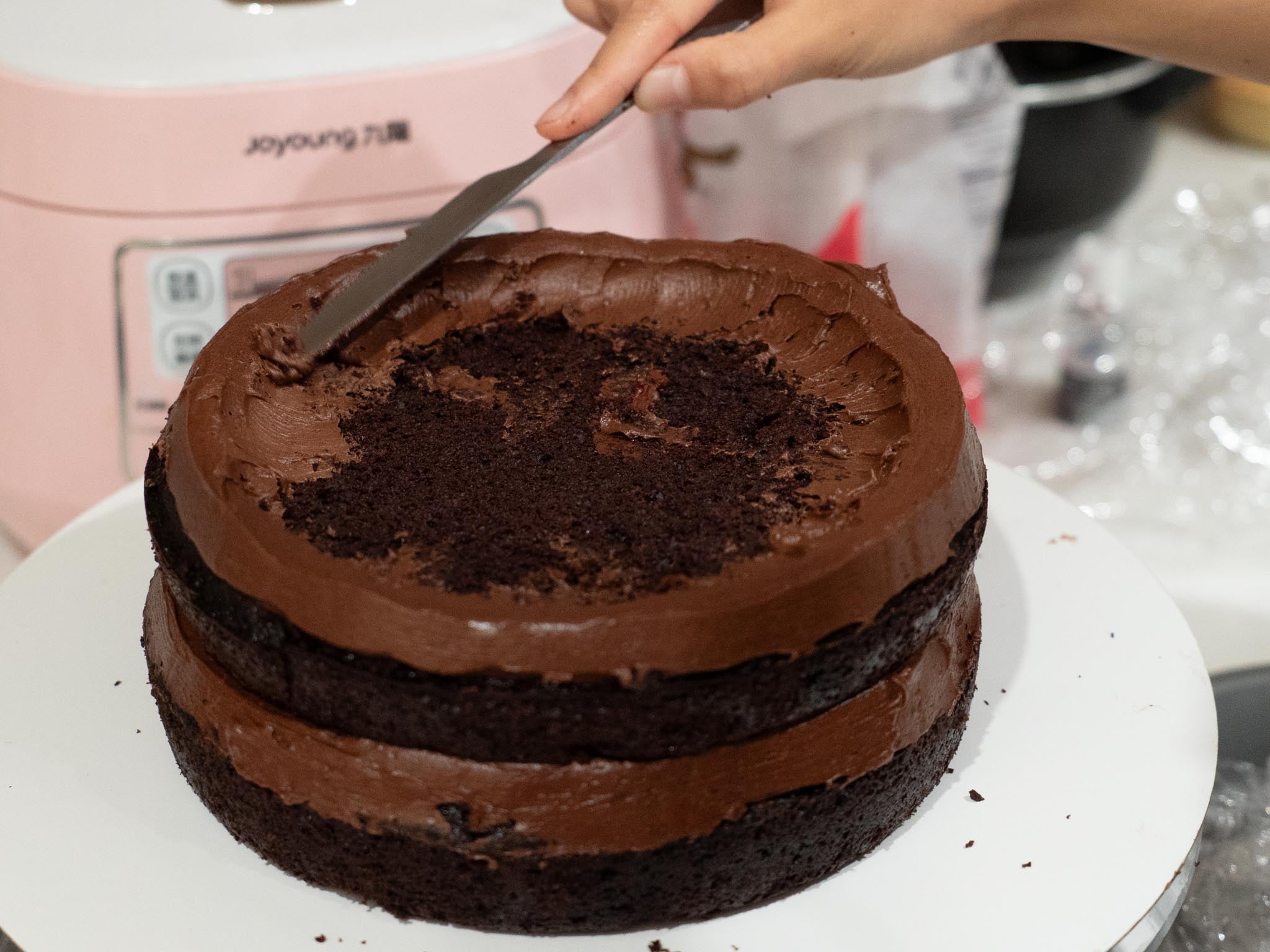 someone using butter knife to smooth down buttercream edge