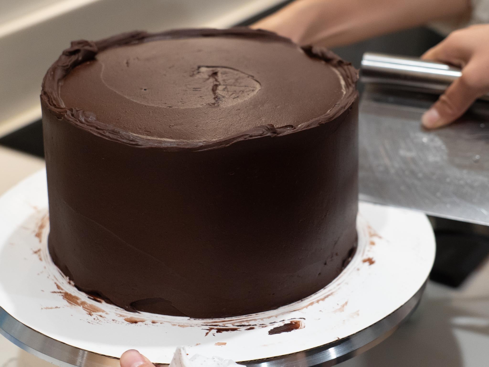 bench scraper scraping off excess chocolate frosting