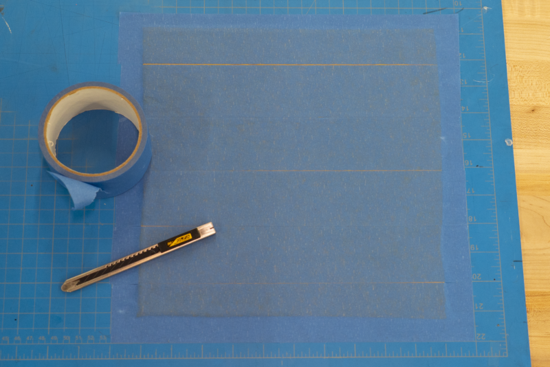 yellow fabric sandwiched between blue tape and hotfix adhesive
