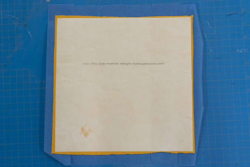 yellow fabric sandwiched between blue tape and hotfix adhesive